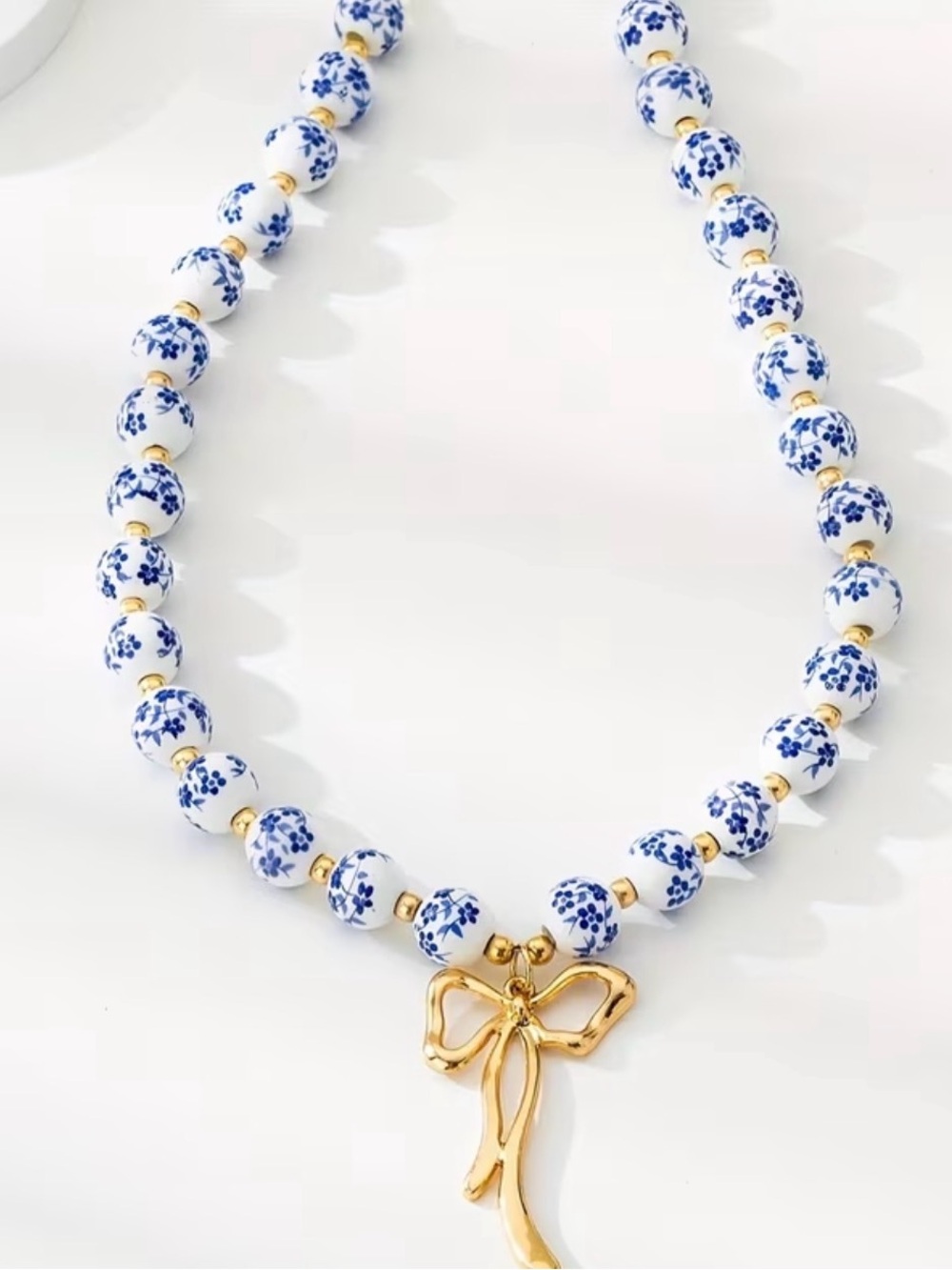 Blue & White Floral Bead Necklace with Gold Bow Pendant